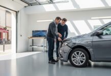 Négocier après un sinistre auto : ce qui est vraiment possible Deux personnes examinant ensemble un pare-chocs endommagé dans un garage lumineux