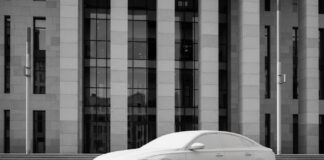 Comment vérifier la solidité financière de son assureur auto Voiture garée devant un bâtiment moderne en pierre et verre, symbole de solidité financière