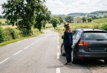 Assurance auto et carte bancaire : les doublons de garanties à repérer Conductrice attendant une assistance routière sur une route de campagne française, à côté de sa voiture en panne