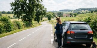 Assurance auto et carte bancaire : les doublons de garanties à repérer Conductrice attendant une assistance routière sur une route de campagne française, à côté de sa voiture en panne