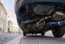 Vol de catalyseur : ce que couvre votre assurance auto et comment réagir Dessous d un véhicule garé dans une rue, ligne d échappement sans catalyseur