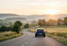 Durée réelle d’un malus assurance auto : comment il s’efface avec le temps Voiture circulant sur une route de campagne au lever du soleil, illustration du retour à une conduite sereine