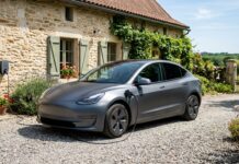 Hybride rechargeable : ce que couvre l’assurance auto sur la batterie Voiture hybride rechargeable branchée à une borne de recharge murale devant une maison en pierre