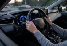 Boîtier télématique et assurance comportementale : comment ça réduit vraiment la prime Boîtier télématique connecté au tableau de bord d une voiture, mains du conducteur sur le volant